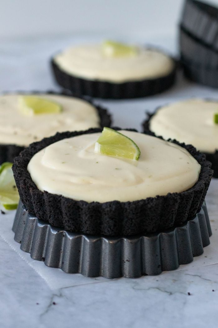 a side view of a lime tart. in the background other lime tarts are arranged